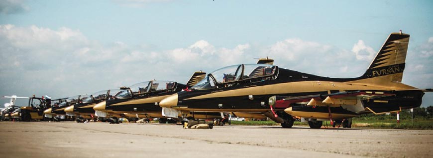 Учебно-тренировочные самолеты Aermacchini MB‑339 пилотажной группы «Аль Фурсан» отдыхают в перерыве между вылетами вместе со своими пилотами. Самолеты окрашены в черный и золотой цвета, символизирующие нефть и золото, обеспечивающие богатство Эмиратов
